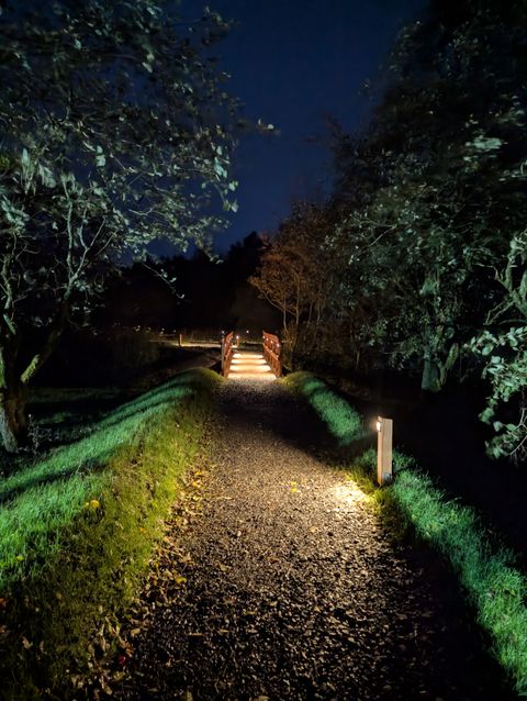 Tarn Sike Woodland Retreat bridge lit up at night which leads to the private lake, Westmorland Dales, Cumbria